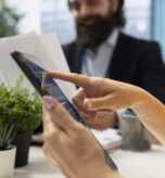 Financial advisor guiding clients in trading shares using software on tablet, making informed investment decisions. Agent offering advice on buying and selling stocks on device online, close up